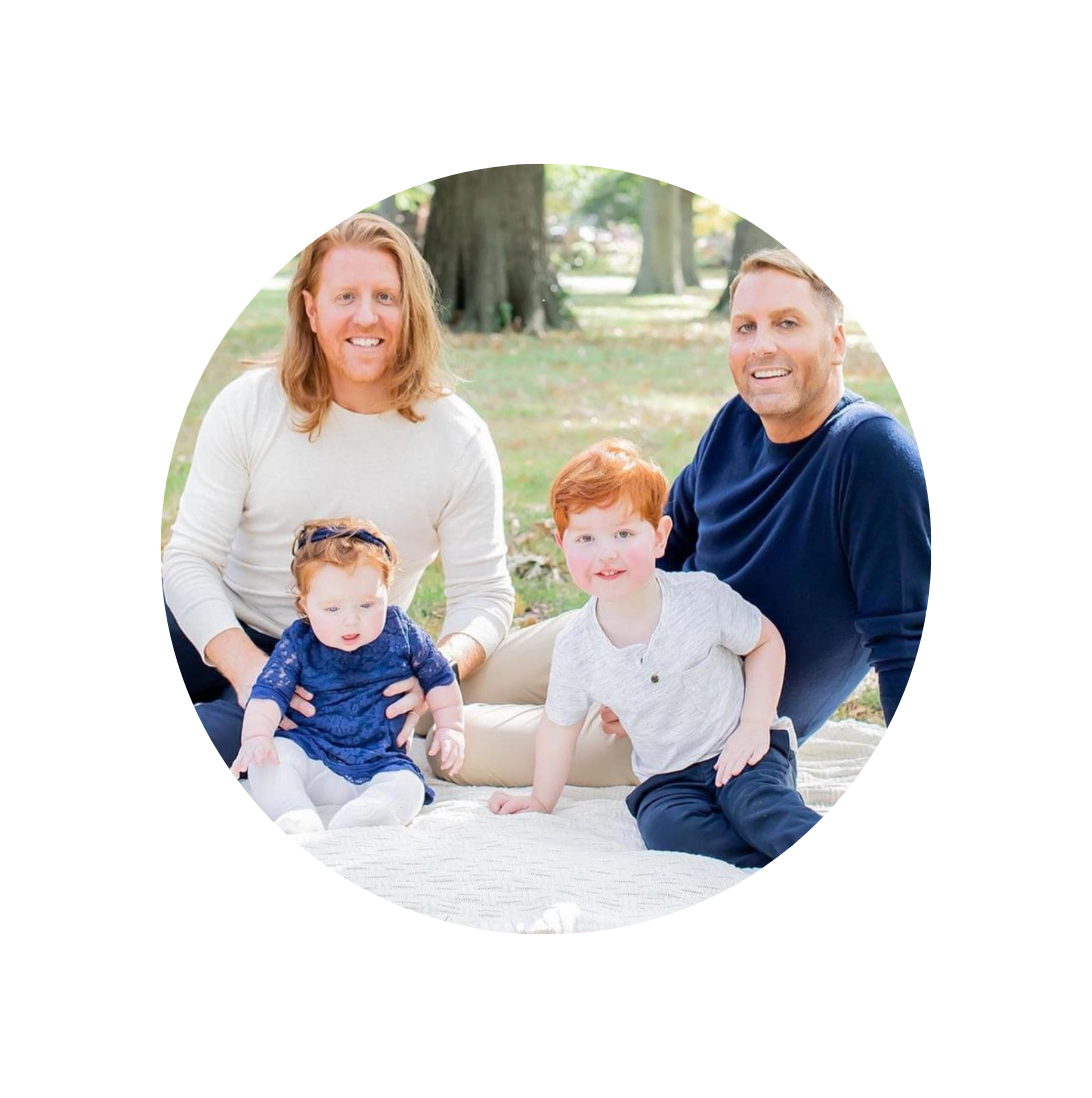 lgbtq dads with two children sitting on blanket