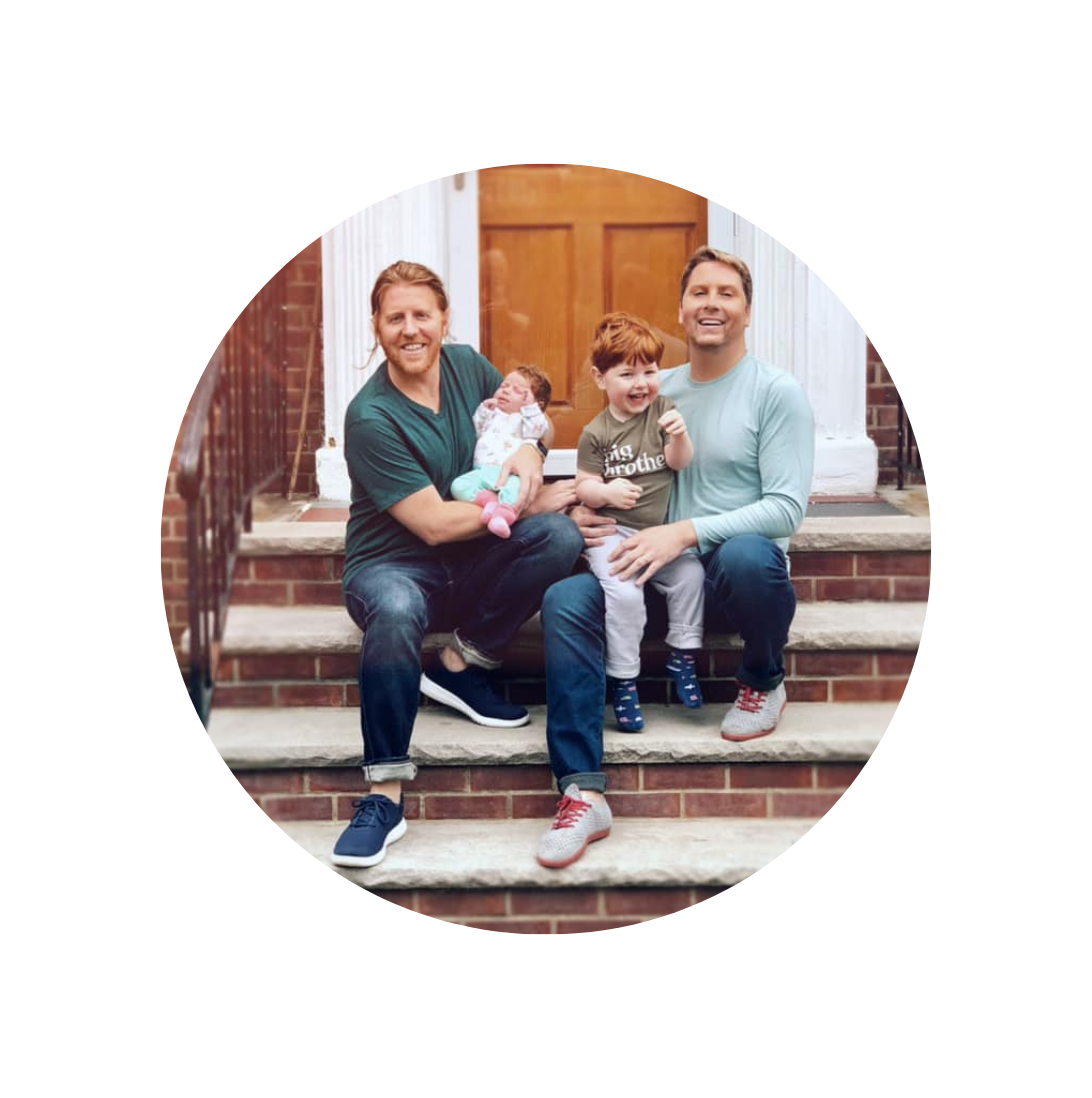 LGBTQ dads with children smiling on steps
