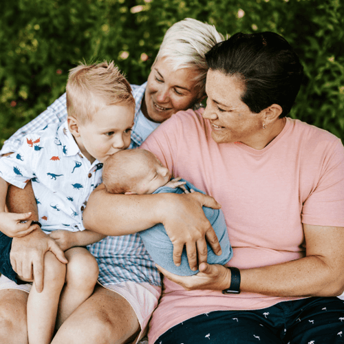 A lesbian couple holds their two sons outdoors
