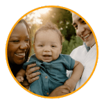 a smiling mother and father hold their infant sun outside