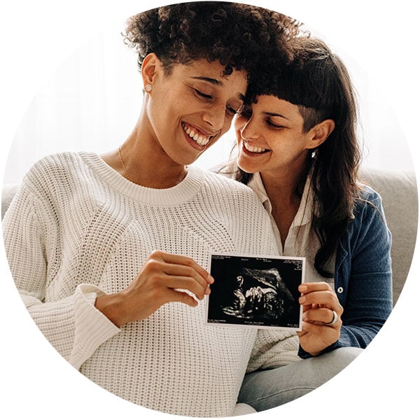 Happy lesbian couple smiling with pregnant belly after INVOcell treatment