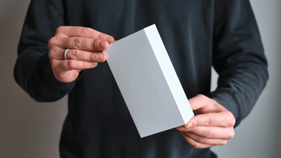 man wearing black sweatshirt holding small white box