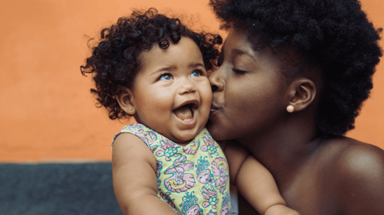 black mother kissing baby girl on cheek