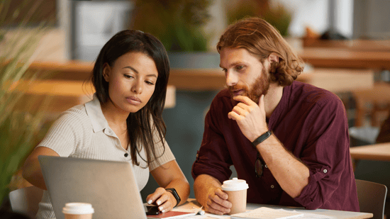 couple-sitting-at-table-looking-at-laptop