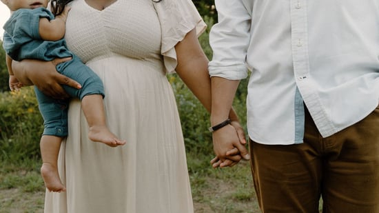 an image of a mother and father holding hands outdoors with mother holding infant son
