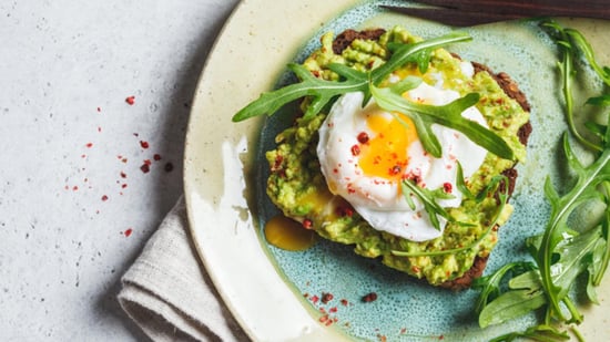 best fertility diet avocado toast with poached egg arugala red chili pepper flakes on teal and beige plate