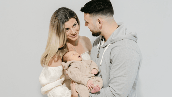 couple looking at each other holding newborn son