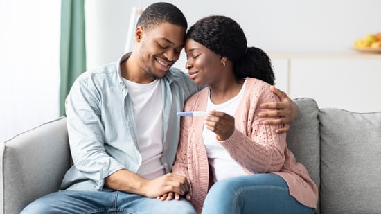 smiling black couple holding positive pregnancy test after IUI procedure