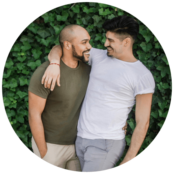Two male partners smiling together while talking about fertility testing options.