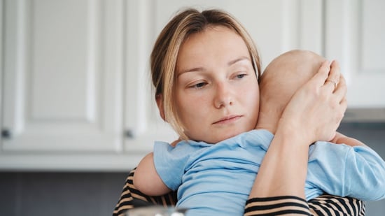 a mother holds and comforts her baby in a kitchen