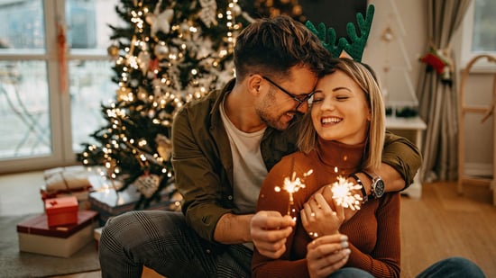 new year happy couple with sparklers in front of christmas tree