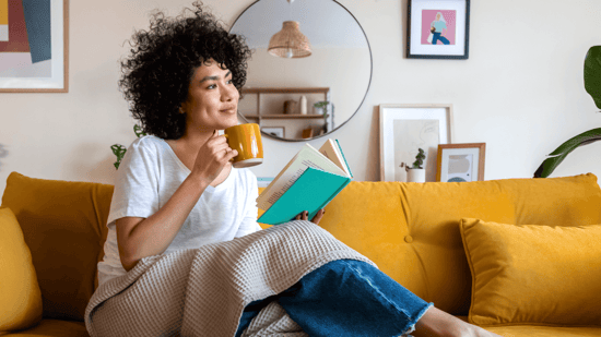 african american woman relaxing on sofa with book