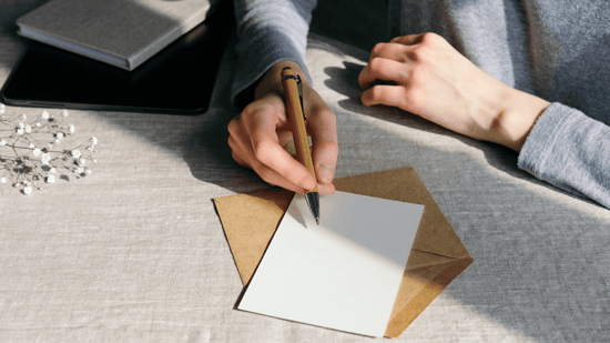 woman writing letter with pen and paper